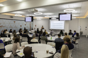 People sit at white circular tables in a seminar room attending a workshop. Photograph from VitaeCon2024.