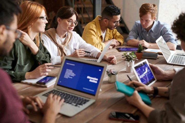 A group of people sit at a table with laptops. Image from Pexels by Fauxels.