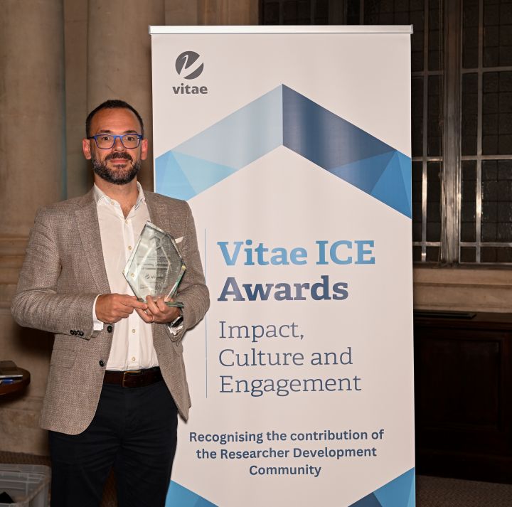 Cosimo Inserra holding his ICE Award in front of the ICE banner.