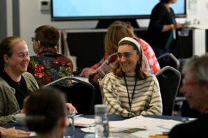 Two women smiling while sat in a workshop. Image from #VitaeCon2025 by Andrew Callaghan.