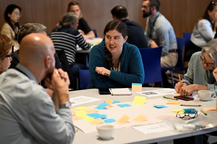 A group of people gathered around a table with post it notes and stationery. Image from #VitaeCon2025 by Andrew Callaghan.