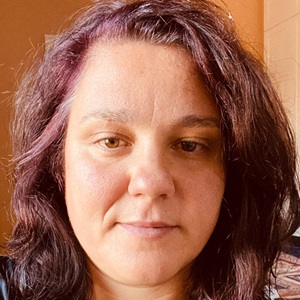 A woman with brown hair looks at the camera.